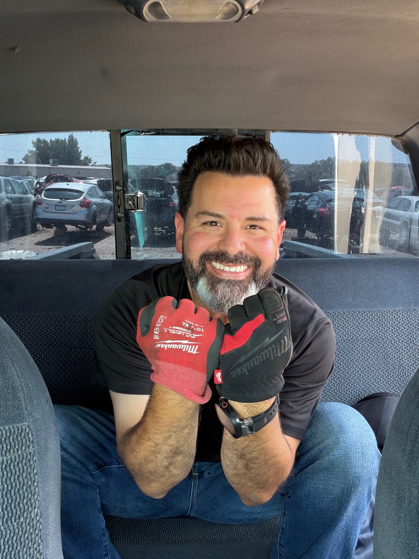 Val smiling in the truck cab with work gloves raised
